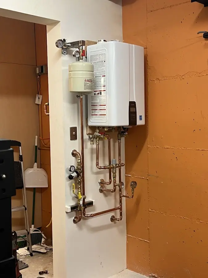 Plumbing technician inspecting water heater connections in Wayne